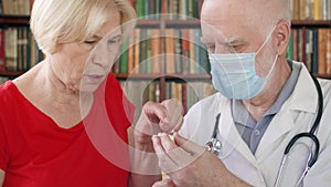 Male professional doctor at work. Senior man physician treat senior female patient giving flu pill