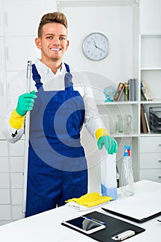 Male professional janitor dusting in office