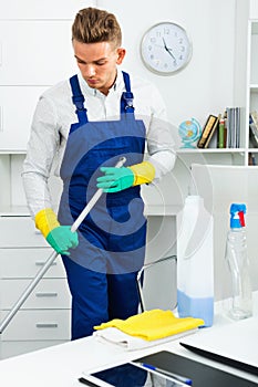 Male professional janitor dusting in office