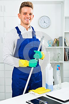 Male professional janitor dusting in office