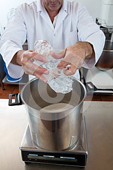 Male professional with white lab coat pouring and weighting glucose