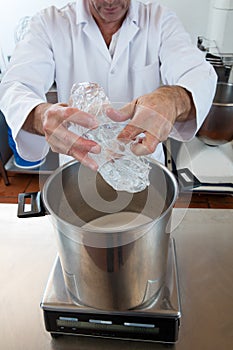 Male professional with white lab coat pouring and weighting glucose photo