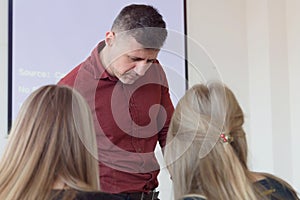 Male professor explain lesson to students and interact with them in the classroom.Helping a students during class. University