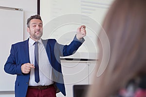 Male professor explain lesson to students and interact with them in the classroom.Helping a students during class. University