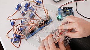 male programmer creates robotics, an arduino board controls servo motors. DIY mechanics, programming through codes on a