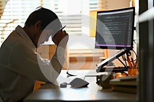 Male programmer looking stressed out while working on difficult project at workplace