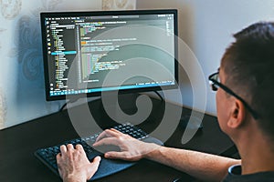 Male programmer working on computer code in modern workspace with focused expression and technology