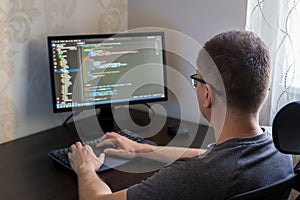 Male programmer working on computer with coding interface and modern workspace design