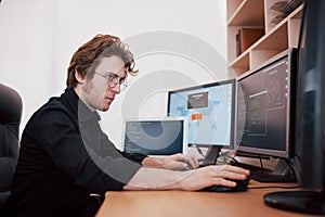 Male programmer working on desktop computer with many monitors at office in software develop company. Website design