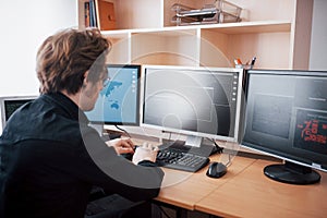 Male programmer working on desktop computer with many monitors at office in software develop company. Website design