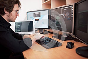 Male programmer working on desktop computer with many monitors at office in software develop company. Website design