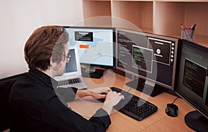 Male programmer working on desktop computer with many monitors at office in software develop company. Website design