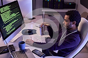 Male IT programmer writing code and using computer at office workplace