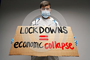 Male protester holding placard against coronavirus lockdowns against grey background