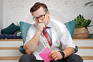 Male psychiatrist with pencil and clipboard sullenly looking into the camera, listening to the patient`s complaints photo