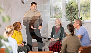 Male psychologist conducting a group session with mature clients