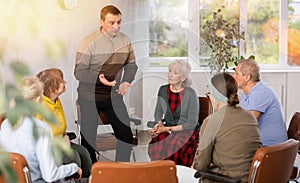 Male psychologist conducting a group session with mature clients