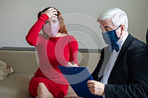 Male psychotherapist advises a female client in a medical mask. Moral support during the epidemic. Depressed woman on a