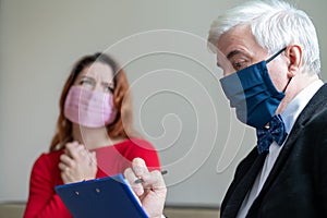 Male psychotherapist advises a female client in a medical mask. Moral support during the epidemic. Depressed woman on a