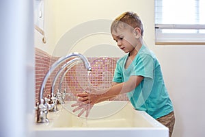 Male Pupil At Montessori School Washing Hands In Washroom