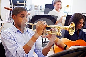 Male Pupil Playing Trumpet In High School Orchestra photo