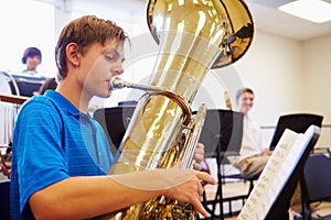 Male Pupil Playing Tuba In High School Orchestra