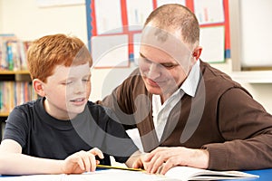 Male Pupil Studying in classroom with teacher