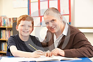 Male Pupil Studying in classroom with teacher