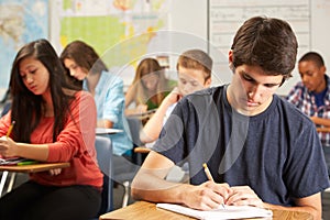 Male Pupil Studying At Desk In Classroom