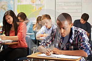 Male Pupil Studying At Desk In Classroom