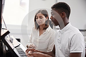 Male Pupil With Teacher Playing Piano In Music Lesson