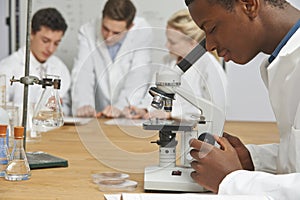 Male Pupil Using Microscope In Science Class