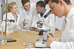 Male Pupil Using Microscope In Science Class