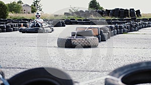 Male racer in protective helmet racing on the go-kart track outdoors