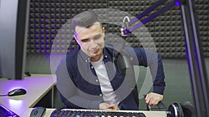 a male radio host conducts a live broadcast in a professional radio studio.