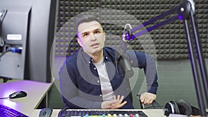 a male radio host conducts a live broadcast in a professional radio studio.