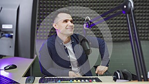 a male radio host conducts a live broadcast in a professional radio studio.