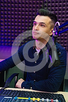 a male radio host conducts a live broadcast in a professional radio studio.