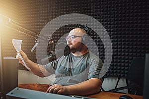 Male radio host with headphones on head and mic in studio reading news or broadcast show