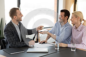 Male realtor give keys to excited Caucasian couple in office
