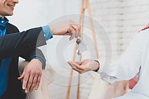 Male realtor gives keys to a realtor in an office.