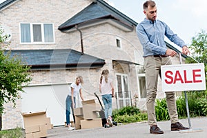 male realtor hanging sale sign in front of people relocating