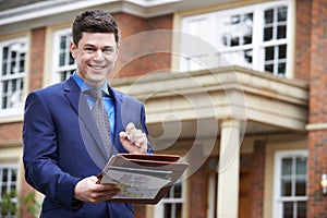Male Realtor Standing Outside Residential Property
