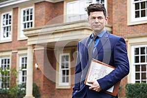 Male Realtor Standing Outside Residential Property photo
