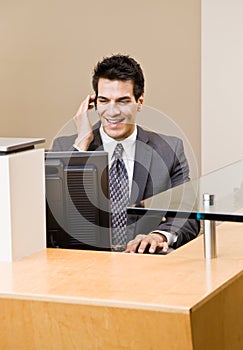 Male receptionist talking on telephone earpiece