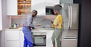 Male Repairman Installing Induction Cooker With Woman Standing