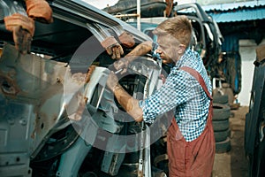 Male repairman poses on car junkyard