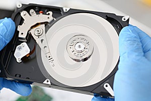 Male repairman wearing blue gloves is holding a hard drive