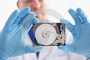 Male repairman wearing blue gloves is holding a hard drive