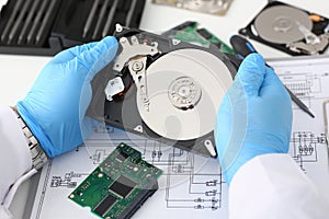 Male repairman wearing blue gloves is holding a hard drive